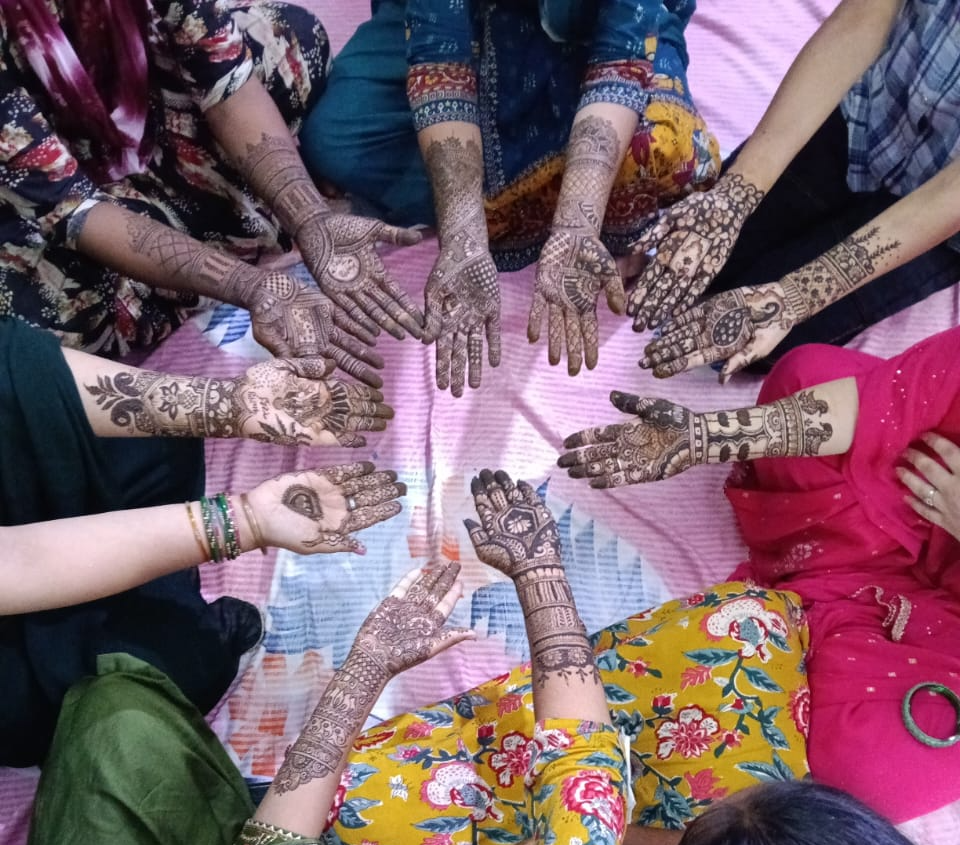 Trainees displaying completed mehndi designs on their hands at a Laksar centre